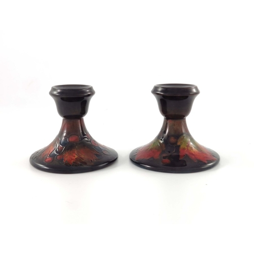 646 - William Moorcroft, a pair of Flambe Leaf and Berry candlesticks, circa 1935, splayed form with ogee ... 