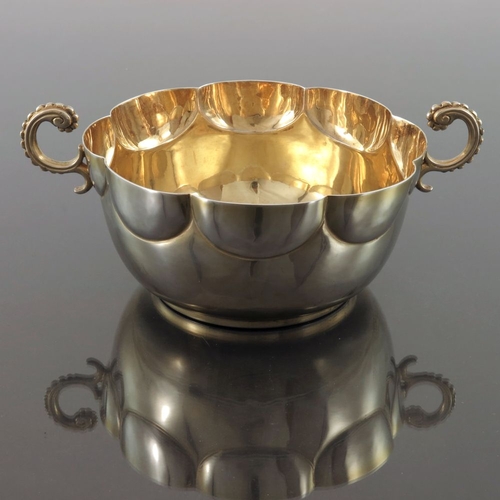 128 - An Edwardian silver gilt twin handled bowl, Pairpoint Brothers, London 1906, rounded with lobed rim ... 