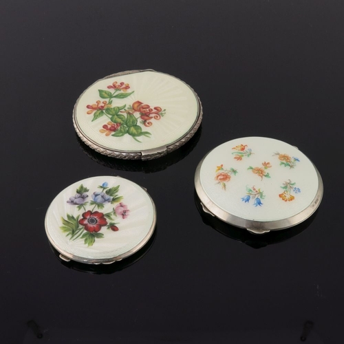 205 - Three silver circular powder compacts, in cream guilloche enamel and painted with various flowers, a... 