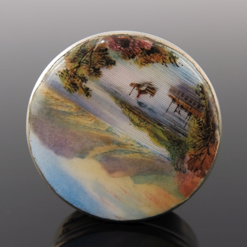 227 - A George V silver circular powder compact, the cover enamelled with a mountainous lake landscape, Bi... 