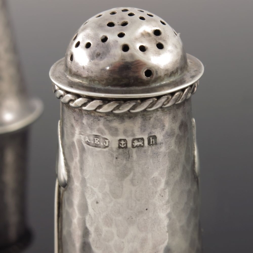 277 - A E Jones, a pair of Arts and Crafts silver pepper pots, Birmingham 1907, planished flared form, app... 