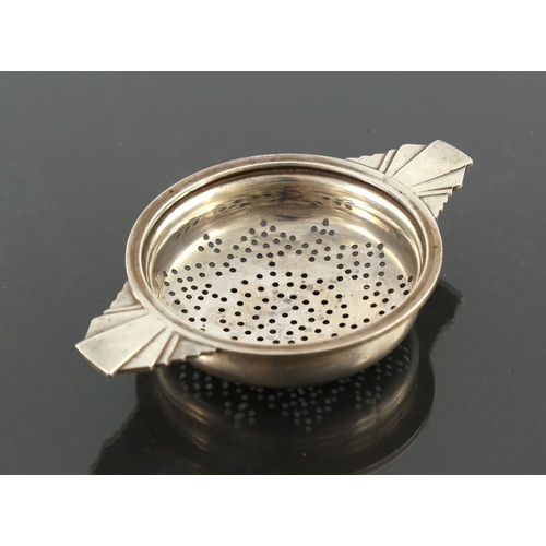 288 - An Art Deco silver tea strainer, Walker and Hall, Birmingham 1936, ogee circular bowl with cast step... 