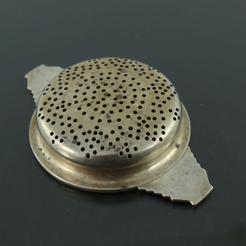 288 - An Art Deco silver tea strainer, Walker and Hall, Birmingham 1936, ogee circular bowl with cast step... 