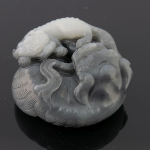 469 - A Chinese black and white jade pendant carving, in the form of large and small shi-shi, diameter 5cm