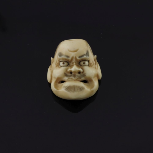 500 - λ A Japanese ivory miniature face mask, Meiji period, 1868-1912, as an angry bearded man, signed, he... 