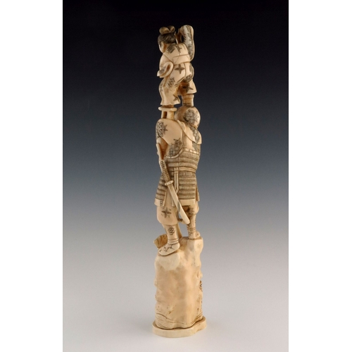 501 - λ A Japanese ivory tusk carving, Meiji period, 1868-1912, carved as a samurai on a rocky outcrop wit... 