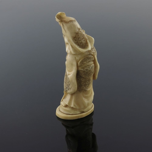 510 - λ A Japanese ivory okimono, Meiji period, 1868-1912, carved as a robed bearded immortal standing hol... 