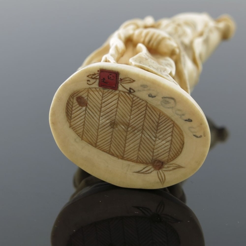 510 - λ A Japanese ivory okimono, Meiji period, 1868-1912, carved as a robed bearded immortal standing hol... 