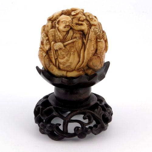 527 - λ A 19th century Japanese carved ivory ball, Meiji, modelled in relief with seated figures in conver... 