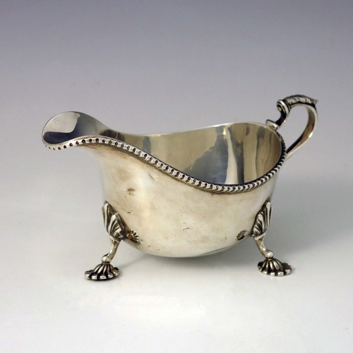 108 - An Elizabeth II silver sauce boat, Adie Brothers, Birmingham 1961, helmet form, on three cast shell ... 