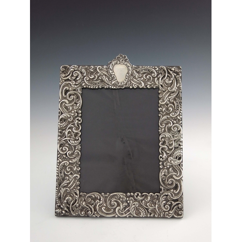 130 - A Victorian silver photograph frame, Charles Dumenil, London 1899, rectangular, embossed in relief w... 