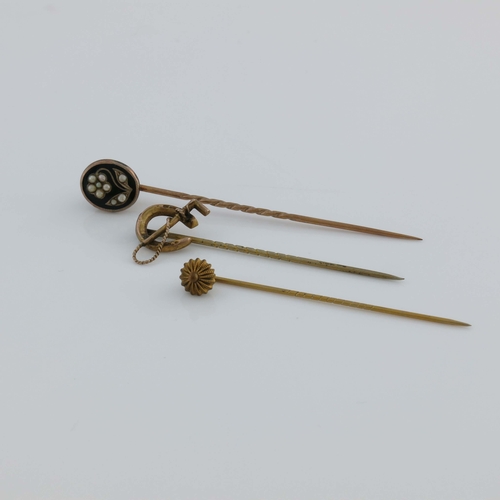 175 - Three yellow metal stick pins, including riding crop and horseshoe, enamel and split pearl floral mo... 