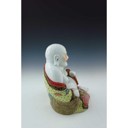 426 - A Chinese ornamental figure of Hotei, seated grinning, partially wearing a robe and clutching a bead... 