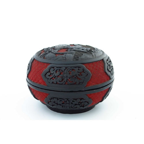 471 - A Chinese red and black lacquer circular covered vessel, carved in high relief with two figures in a... 