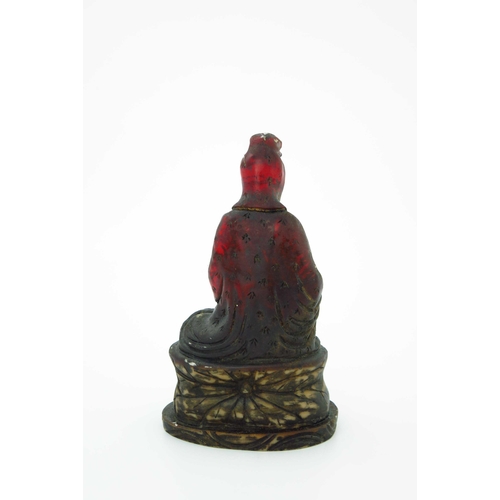 472 - A Chinese moulded red translucent figure of a seated female deity, raised on a lotus leaf, gilt remn... 