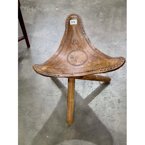 512 - A folding tripod stool with embossed leather saddle seat.