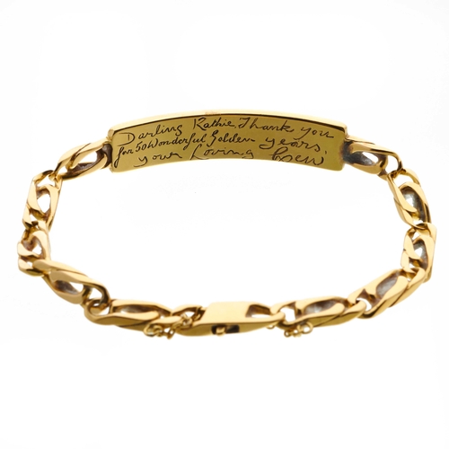 25 - An 18ct gold flat curb-link identity bracelet, with rectangular-shape curved panel and lobster clasp... 