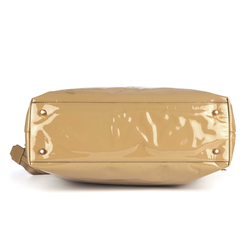 267 - Anya Hindmarch, a beige patent leather handbag, featuring gold-tone hardware, studded bow logo embel... 