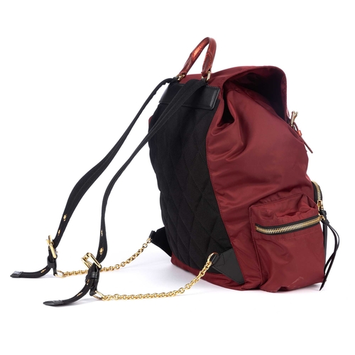 282 - Burberry, a red nylon backpack, featuring metallic red leather trim and gold-tone hardware accents, ... 