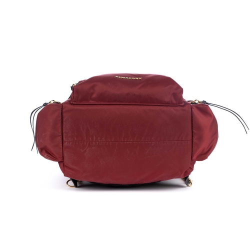 282 - Burberry, a red nylon backpack, featuring metallic red leather trim and gold-tone hardware accents, ... 