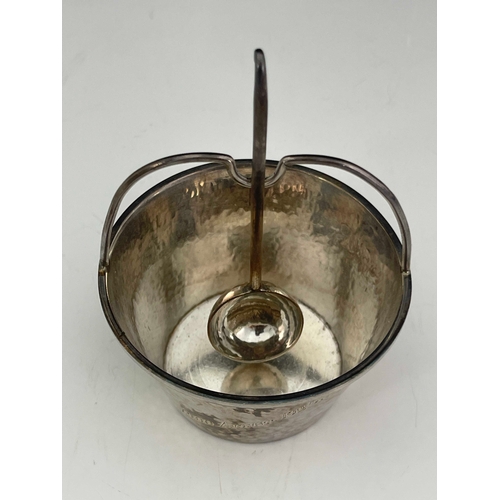 243 - An Arts and Crafts silver sugar bowl and spoon, A E Jones, Birmingham 1924, planished conical pail f... 