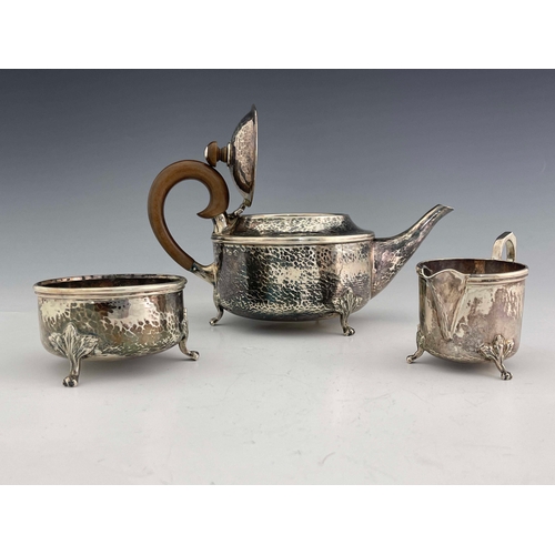 251 - A E Jones, an Arts & Crafts silver three piece tea set, Birmingham 1918, planished cylindrical form,... 