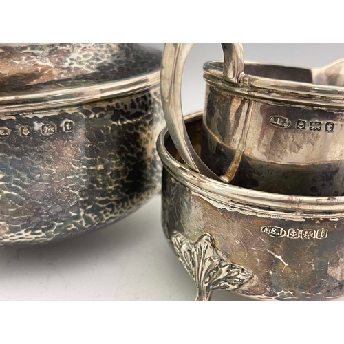 251 - A E Jones, an Arts & Crafts silver three piece tea set, Birmingham 1918, planished cylindrical form,... 