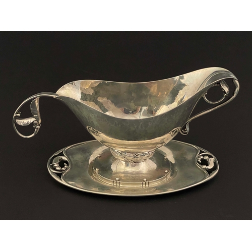 253 - George Jensen, a Danish Jugendstil silver Magnolie pattern sauce boat, stand and spoon, model No 177... 