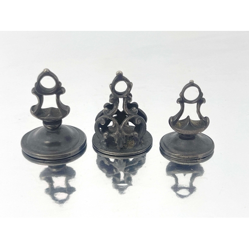 296 - Three Georgian pewter pocket seal fobs, scroll mounts with ring suspension hooks, one with intaglio ... 