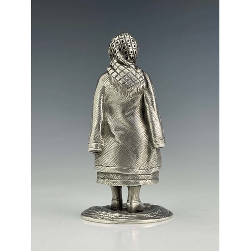 45 - A Scottish silver pepper caster, W H & S Edinburgh 1926, in the form a lady standing with arms cross... 