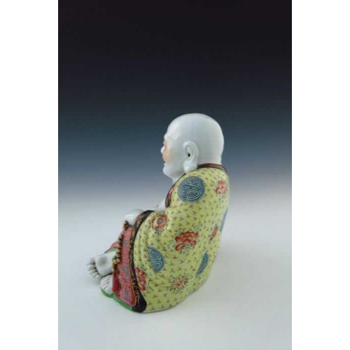 391 - A Chinese ornamental figure of Hotei, seated grinning, partially wearing a robe and clutching a bead... 