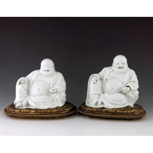 392 - A pair of Chinese blanc de chine Buddhas, 19th Century, the smiling figures seated in repose with op... 