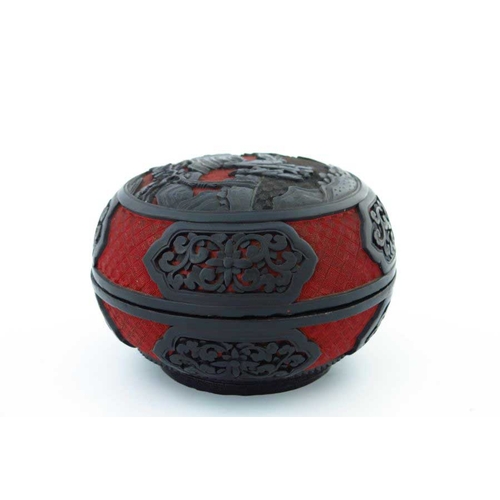 411 - A Chinese red and black lacquer circular covered vessel, carved in high relief with two figures in a... 