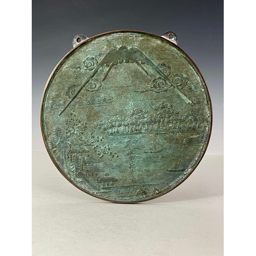 418 - A Japanese bronze roundel wall plaque, cast with a landscape scene with pagodas and boats on a lake ... 