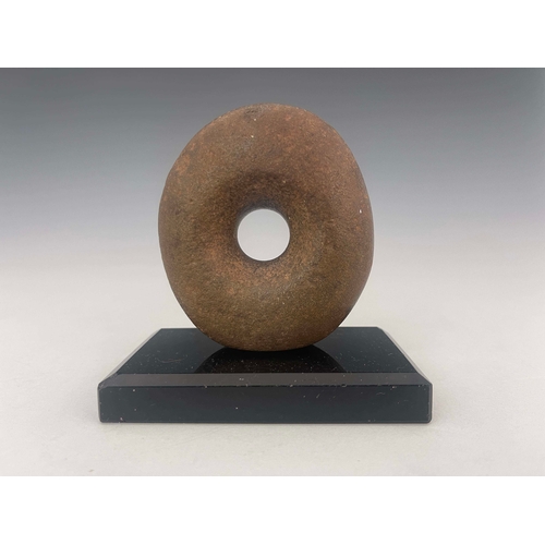 445 - A stone age mace head, of distorted oval form with off-central hole, 9cm high, mounted