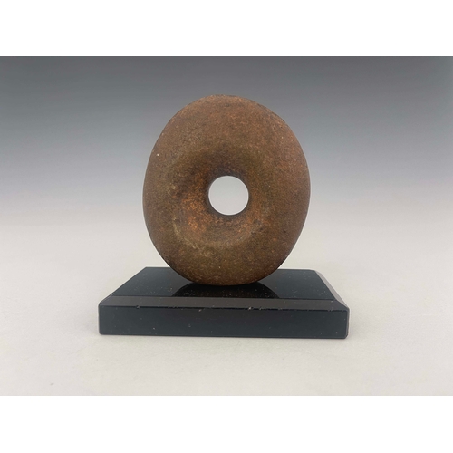 445 - A stone age mace head, of distorted oval form with off-central hole, 9cm high, mounted