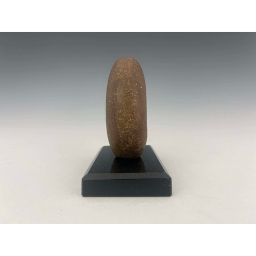 445 - A stone age mace head, of distorted oval form with off-central hole, 9cm high, mounted