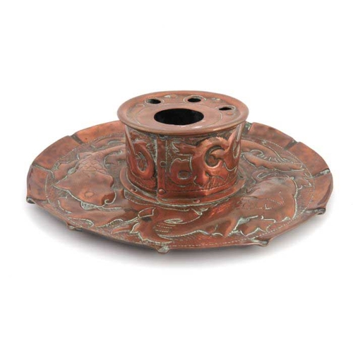 501 - An Arts and Crafts Cornish copper inkwell, Newlyn style, the circular dish repousse decorated with f... 