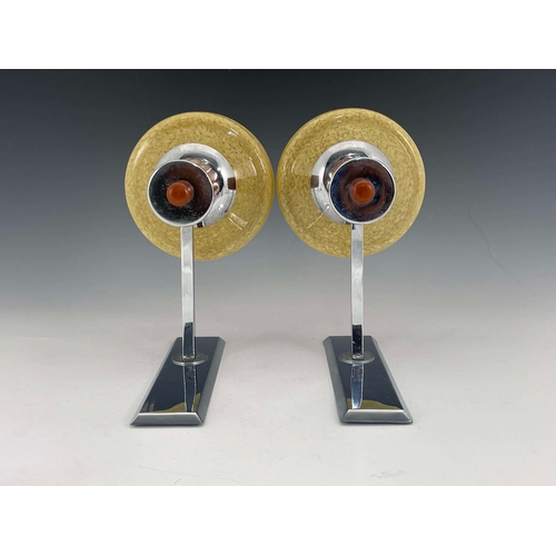 522 - A pair of Art Deco chrome and glass wall lights, with fluted amber coloured Bakelite supporting yell... 