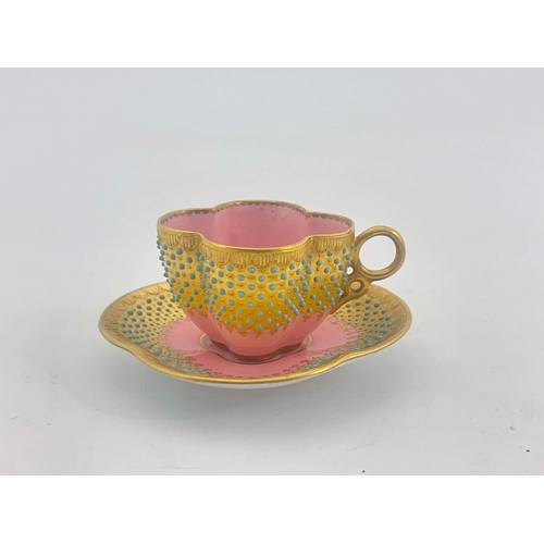 911 - A Coalport jewelled and gilded cup and saucer, quatrelobed with bands of graduated turquoise cabocho... 