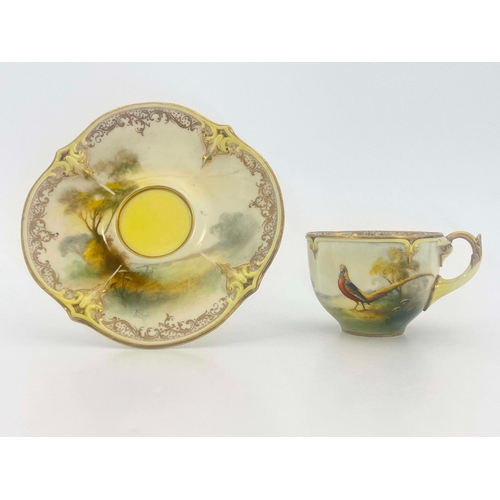 928 - Hadley's Worcester, a cabinet cup and saucer, lobed and painted with a pheasant in open countryside,... 