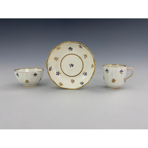 961 - A Caughley tea trio, circa 1790, reeded tea bowl and coffee cup, painted with French Sprigs in polyc... 