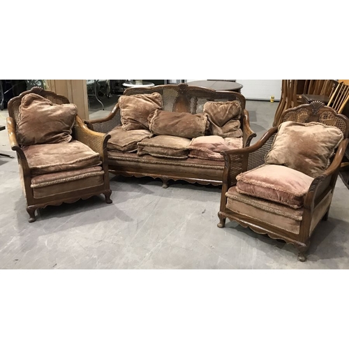 820 - A walnut three piece bergere suite, circa 1920s, with anthemion carved back rail and outswept frame,... 