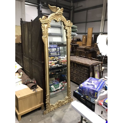 823 - A carved giltwood wall mirror, with carved bird pediment and faux marbled panels, 220cm High x Max 6... 