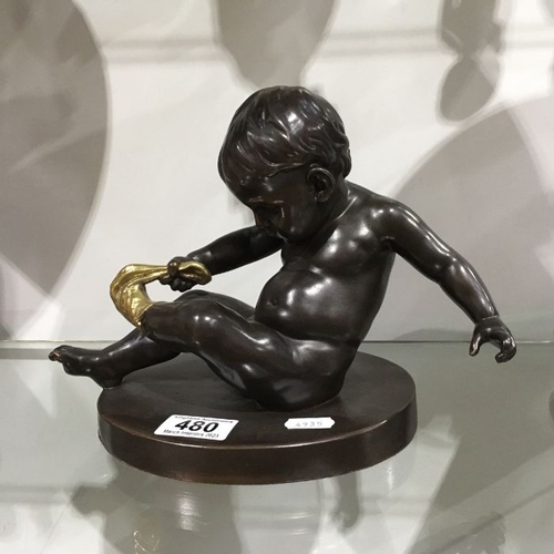 480 - A bronzed and gilt sculpture, modelled as Cupid removing a sock