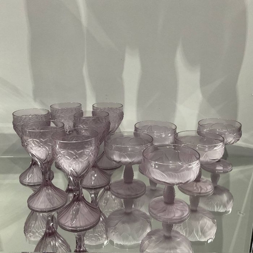 488 - A part suite of moulded purple glass goblets and pedestal dishes, frosted and modelled with floral b... 