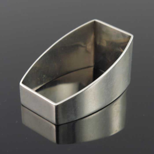 174 - A Modernist silver napkin ring, ABC, London 1979, barrel section, wedge form, applied with an initia... 