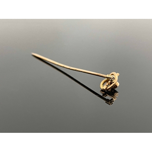 181 - A 9 carat gold and pink gem set stick pin, the knotted wire head set with a facet cut stone, 5.5cm l... 