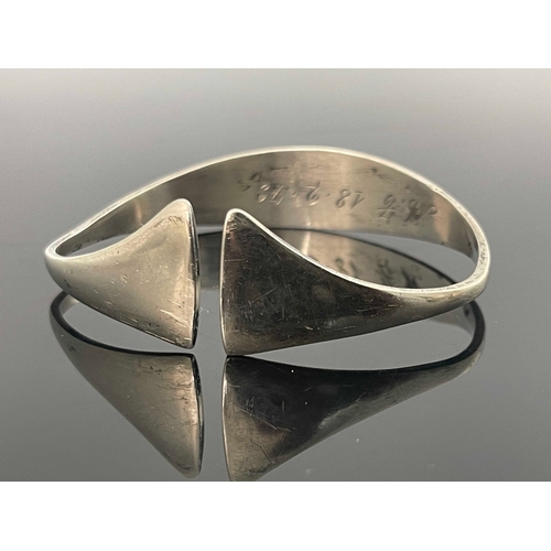 186 - A Modernist silver bangle, circa 1972, stylised torque form with axe head ends, 6.5cm wide, 0.92ozt