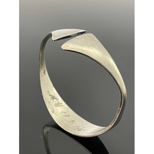 186 - A Modernist silver bangle, circa 1972, stylised torque form with axe head ends, 6.5cm wide, 0.92ozt